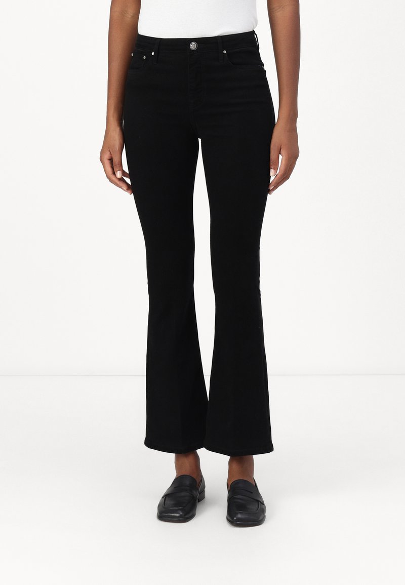 Melnas zābakveida bikses ar augstu jostasvietu, kas aprīkotas ar piecām kabatām, metāla pogu aizdari un mīkstu, nedaudz teksturētu audumu.