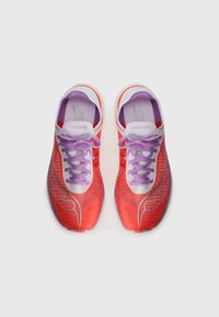 Des chaussures de sport rouges et violettes avec une tige en mesh respirant, des lacets légers, des accents réfléchissants et une semelle cushioned.