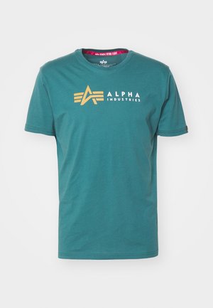 Turkusowa bawełniana koszulka z krótkim rękawem. Złote logo i napis "ALPHA INDUSTRIES" na przodzie. Klasyczny okrągły dekolt.