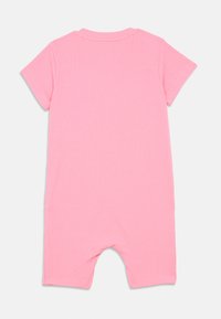 Vista traseira de um macacão de bebé rosa de mangas curtas, feito de tecido canelado, com decote redondo e pernas curtas.