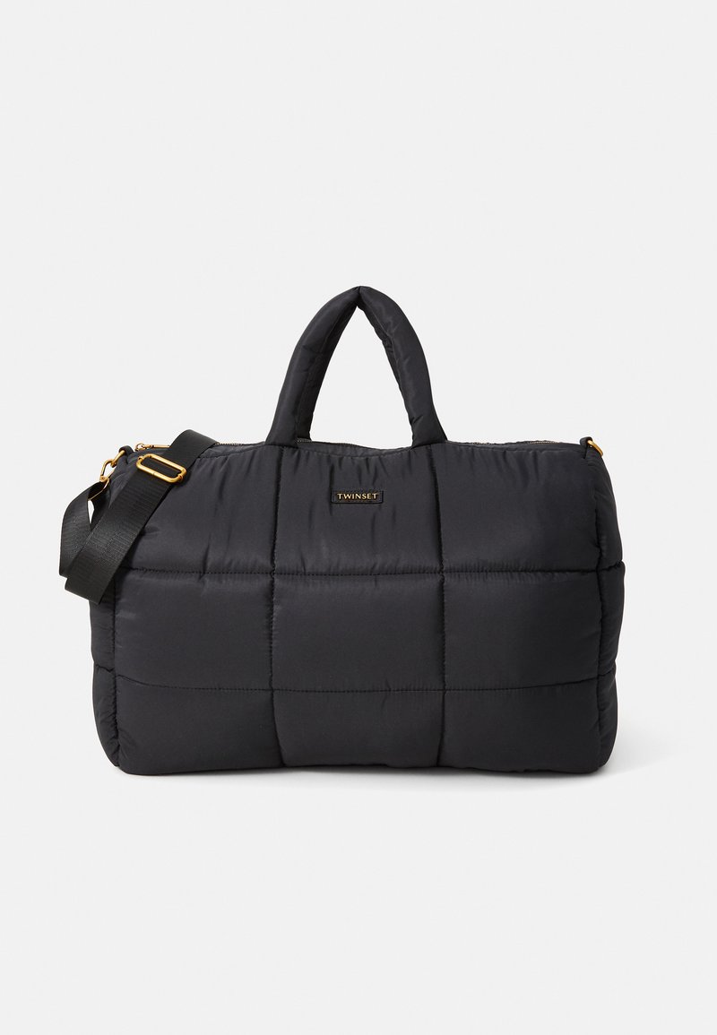 Black quilted duffle bag with padded handles, adjustable shoulder strap, and gold "Twinset" logo plaque on front.
