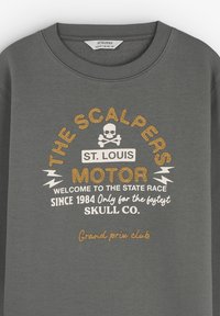 Sudadera gris con calavera y huesos cruzados, rayos y texto: "Los Scalpers St. Louis Motor Bienvenido a la carrera estatal desde 1984."