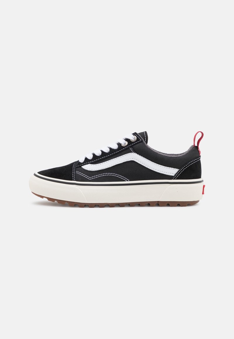 Zapatillas de lona negras con acentos blancos, punta redonda, cordones blancos, suela gruesa color crema y un lazo rojo en el talón para facilitar su uso.