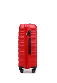 Maleta rígida roja con textura acanalada vertical, asa superior, cierre de cremallera negro y cuatro ruedas para mayor estabilidad.