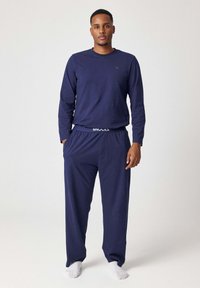 Marineblauw lange mouwen top en bijpassende pyjamabroek gemaakt van zachte stof. De broek heeft een elastische tailleband met de opdruk "SNOCKS".