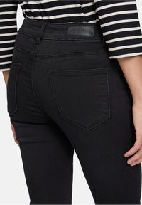 Czarne dżinsy o wysokim talii, gładkiej fakturze i dyskretnych tylnych kieszeniach. Metka z napisem "Betty Barclay" na pasku.