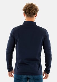 Polo shirt lungo navy con colletto, caratterizzato da una texture liscia e un design aderente, visto da dietro con dettagli minimi.