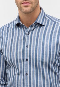 Blauw-wit gestreept shirt met kraag, voorzien van een knoopsluiting aan de voorkant en een gestructureerde stof. De knopen zijn donkerblauw en de strepen variëren in breedte.