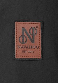 Braunes Lederetikett mit schwarzem, geprägtem Text "NAVAHOO" und "EST 2014" auf einem schwarzen Stoffhintergrund, mit sauberem Stich entlang der Kanten.