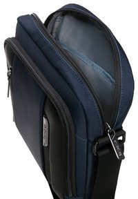 Borsa a tracolla blu navy e nera con due scomparti con zip, tracolla regolabile e tirazip in metallo con logo.