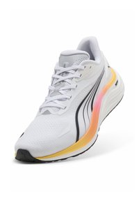 Λευκό αθλητικό παπούτσι με επάνω μέρος από δίχτυ, με μαύρες και ροζ λεπτομέρειες. Η σόλα είναι κίτρινη, με στρογγυλεμένο σχήμα και υφή σχεδίου.