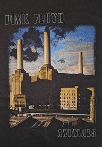 Battersea Power Station s kouřovými komíny, tmavými mraky, modrou oblohou a létajícím prasetem, s texty "Pink Floyd" a "Animals".