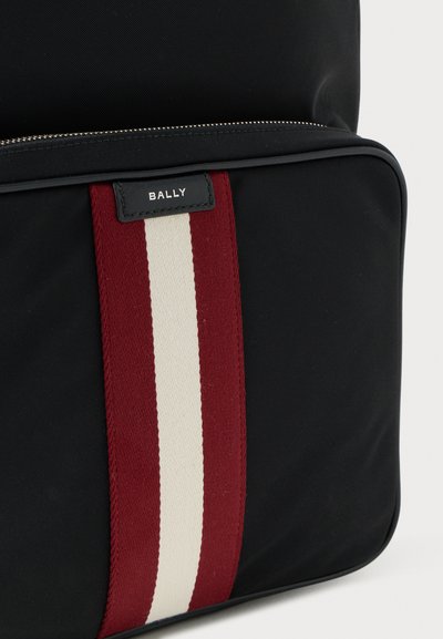 Black fabric bag with a red and white striped accent; features a silver zipper and a black label reading "BALLY." Smooth texture.