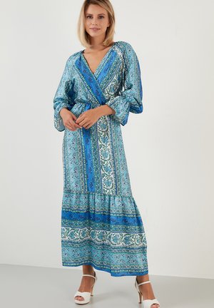 Blue patterned maxi dress with a V-neck, elastic waist, long sleeves, and tiered hem. Features various shades of blue and green floral designs.