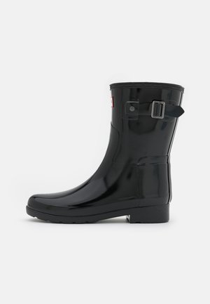 Botte de pluie en caoutchouc noir avec une finition brillante, détail de boucle sur le côté, et une semelle texturée pour l'adhérence. Hauteur mi-mollet.