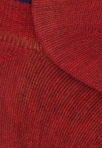 Tessuto a maglia rosso con un motivo strutturato. Il materiale appare morbido e leggermente elastico, con un dettaglio di bordo sovrapposto.