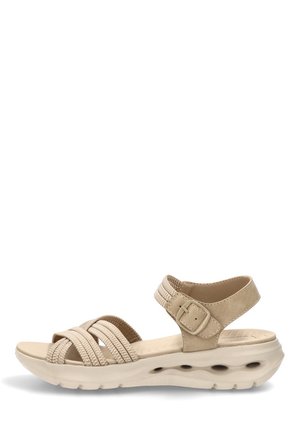 Sandalia beige de punta abierta con correa ajustable en el tobillo, suela acolchada con orificios de ventilación y tiras delanteras tejidas sobre fondo blanco.