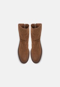Botas de cuero marrón con un diseño arrugado, puntera redondeada y cierre con cremallera. Textura suave con un brillo sutil y suela contrastante.