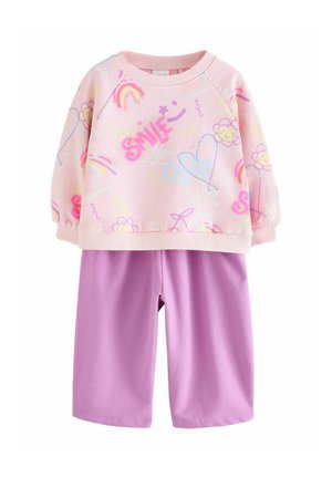 Rosa Sweatshirt mit bunten Mustern, darunter Herzen, Blumen und Regenbögen, kombiniert mit einfarbigen lila Shorts, beide aus sanftem Material.