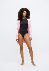 Μαύρο μαγιό με ψηλό λαιμό που συνδυάζεται με ροζ ανοιχτό, μεταξωτή ρόμπα. Η ρόμπα έχει μακριά μανίκια και ελαφρώς διάφανη υφή.