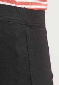 Schwarze, taillierte Hose aus einem strukturierten, dehnbaren Stoff. Verfügt über einen glatten Bund und vertikale Nahtdetails für zusätzliche Struktur.