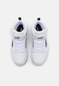 Baskets montantes blanches en cuir synthétique avec des motifs perforés, des accents noirs et un col rembourré. Présentent des lacets et un logo de marque.