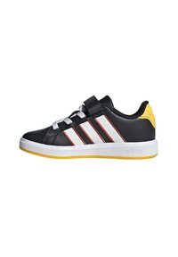 Scarpe atletiche nere con strisce bianche e rosse, lacci argentati, cinturino in velcro, dettaglio giallo sul tallone e suola bianca. Materiale sintetico liscio.