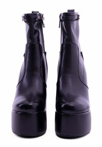Stivali neri in pelle con tacco alto e suola platform, cerniere laterali e texture liscia. Caratterizzati da un design aderente e una silhouette elegante.