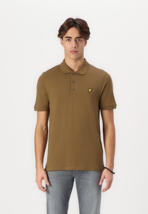 Braunfarbiges Poloshirt aus Baumwolle mit einer Drei-Knopf-Leiste und kurzen Ärmeln, das ein kleines gelbes Logo auf der linken Brust aufweist.