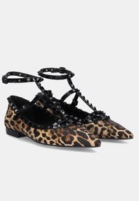 Bailarinas de punta afilada con estampado de leopardo y correas de charol negro adornadas con tachuelas cuadradas y hebillas en el tobillo.