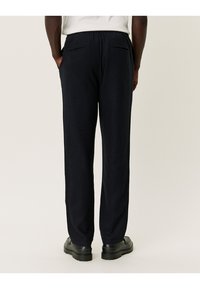 Pantalons noirs, coupe décontractée avec taille élastique, deux poches arrière et design à jambe droite, fabriqués à partir d'un tissu doux et texturé.