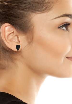 Orecchini a bottone a forma di cuore neri con una finitura testurizzata, indossati all'orecchio, che mostrano un design pulito e semplice.