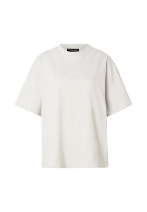 T-shirt ample beige clair à manches courtes avec col rond et petit texte logo blanc centré près de la poitrine.