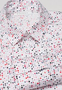 Camicia bianca con pois multicolore in rosso, nero, rosa e beige, con bottoni frontali e polsini ripiegati.