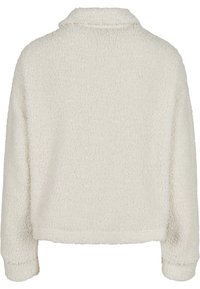 Veste polaire blanche à manches longues texturée avec col montant, vue de dos.
