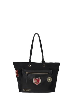 Bolsa tote negra con asas largas, bolsillo frontal con cremallera y parches decorativos que incluyen un escudo rojo, una estrella y una etiqueta con la inscripción C-251, KM.
