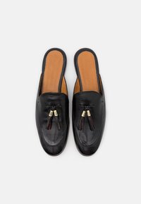 Chaussures noires en cuir à enfiler avec une texture lisse et un bout arrondi. Dotées de glands décoratifs et d'accents en métal doré.