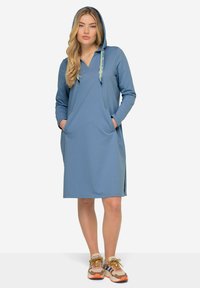 Robe à capuche bleue en tissu doux, dotée d'un décolleté en V, de deux poches latérales et de cordons de tirage à motif vert. Accentuée de fentes sur les côtés.
