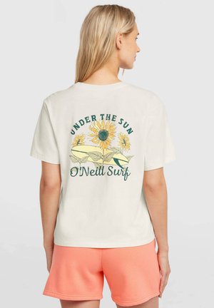 Tricou de culoarea crem cu grafică colorată cu floarea-soarelui, inscripția „UNDER THE SUN” și textul „O'Neill Surf” pe spate; purtat cu pantaloni scurți de culoarea piersicii.