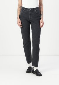Augstās jostas vietas melni džinsi ar taisnu piegriezumu, ar priekšējām kabatām, jostu cilpiņām un redzamu pogas aizdari.