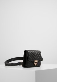 Borsa a tracolla in pelle nera con motivo a chevron trapuntato, chiusura in metallo dorato e tracolla regolabile. Forma rettangolare compatta.