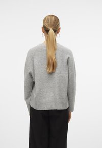Light gray sweater with a ribbed hem, round neckline, and long sleeves. Fabric appears soft, with a relaxed fit and subtle texture.