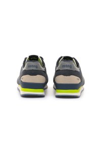 Par de zapatillas azul marino y beige con acentos en amarillo neón, vistas desde la parte de atrás, con "mtng" y "1967" impresos en los talones.