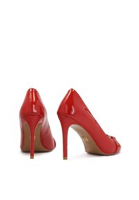 Pantofi cu toc înalt din piele patent roșie, cu vârf ascuțit și detalii delicate din aur; finisaj lucios și siluetă elegantă.