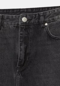 Le jean en denim noir présente un design classique à cinq poches, une fermeture par bouton en métal, et des coutures visibles sur la taille et les coutures.