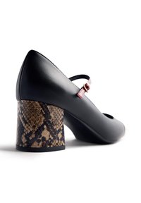 Black leather Mary Jane shoe with a red strap and a chunky brown snakeskin patterned block heel on a white background.