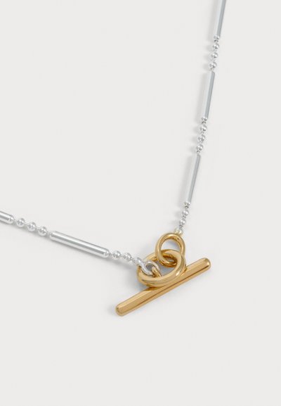 Collier chaîne argenté à maillons allongés et à fermoir toggle doré, présenté sur un fond blanc uni.