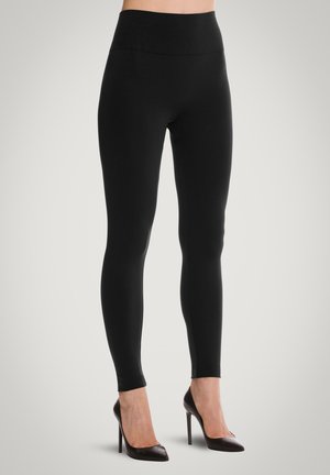 Zwarte legging met een hoge tailleband, gladde stof en een rekbaar fit, gecombineerd met puntige hoge hakken.