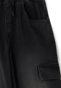 Zwarte denim cargobroek heeft een zachte textuur, een elastische tailleband, zijzakken en een knoopdetails op een opgestikte zak.