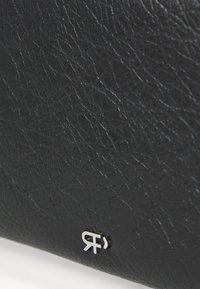 Portafoglio in pelle nera dal texture effetto, con un piccolo dettaglio del logo in argento. La superficie presenta un motivo piegato, evidenziando la qualità del materiale.